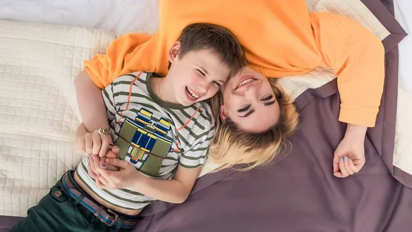 Madre con hijo en la cama, madre e hijo divirtiéndose —  Fotos de Stock