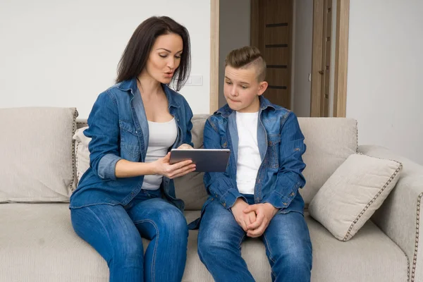 Счастливая семья, сидящая на диване и пользующаяся цифровым планшетом дома — стоковое фото