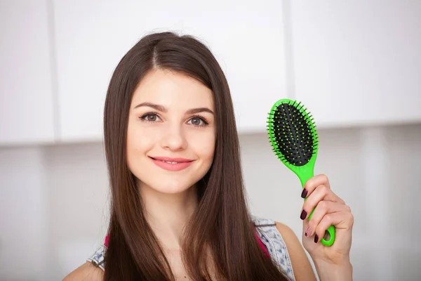 Menina segura uma escova de cabelo sem cabelo e sorrindo — Fotografia de Stock