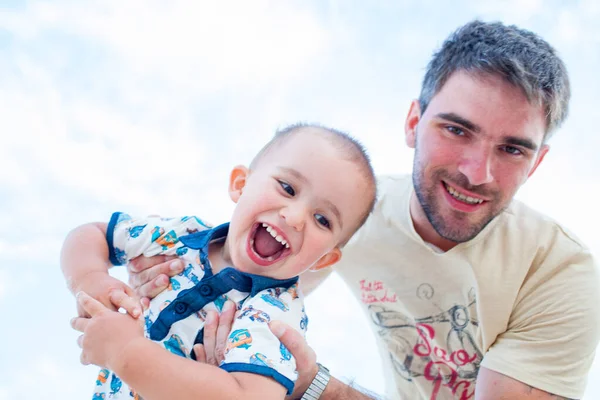 Father having fun with son against blue sky — Stockfoto