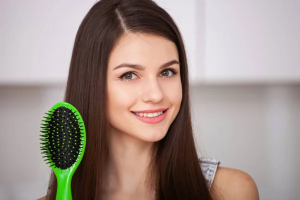 Menina segura uma escova de cabelo sem cabelo e sorrindo — Fotografia de Stock