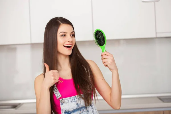 Menina segura uma escova de cabelo sem cabelo e sorrindo — Fotografia de Stock
