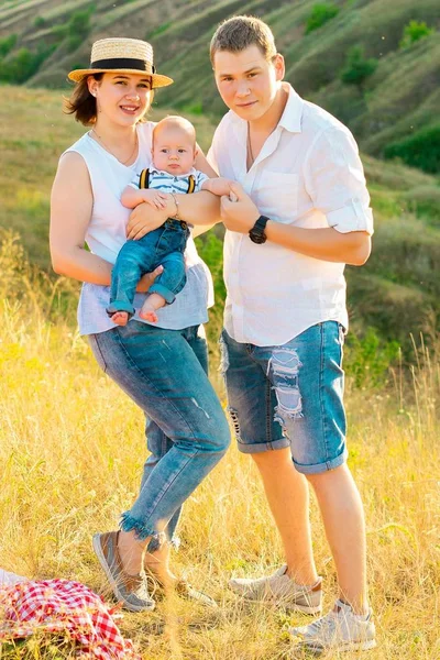 Familia feliz con el pequeño bebé pasando tiempo juntos al atardecer —  Fotos de Stock