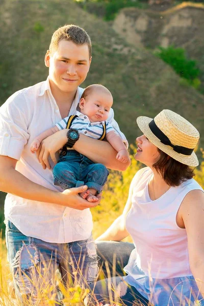Família com bebê no pôr do sol de verão. — Fotografia de Stock