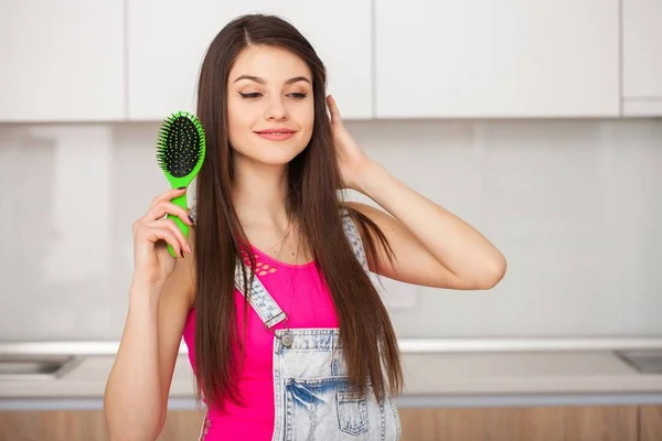 Menina segura uma escova de cabelo sem cabelo e sorrindo — Fotografia de Stock