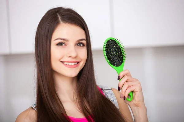 Menina segura uma escova de cabelo sem cabelo e sorrindo — Fotografia de Stock