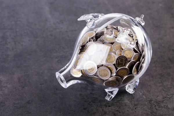 Glass piggy bank with coins inside — Stock Photo, Image