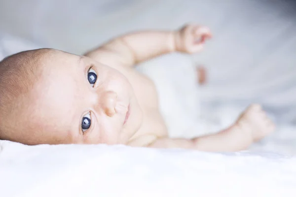 Schönes kleines Mädchen auf weißer Decke — Stockfoto