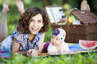 Genç güzel anne kızıyla birlikte park battaniyeye oturur