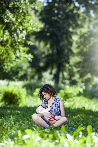 Молоді материнські груди годують дитину в парку — стокове фото