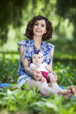 Genç güzel anne kızıyla birlikte park battaniyeye oturur