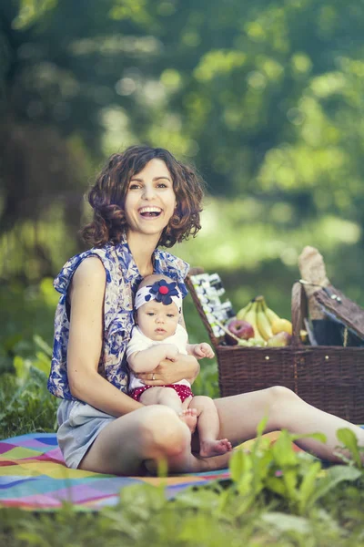 Genç güzel anne kızıyla birlikte park battaniyeye oturur