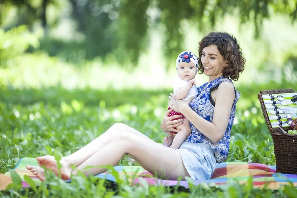 Genç güzel anne kızıyla birlikte park battaniyeye oturur