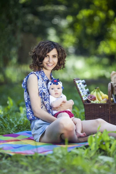 Genç güzel anne kızıyla birlikte park battaniyeye oturur