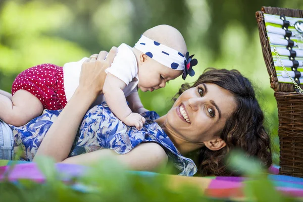 Genç anne ile bebek battaniye parkta oynarken