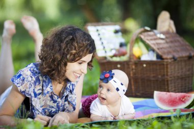 Genç güzel anne kızıyla birlikte park battaniyeye oturur