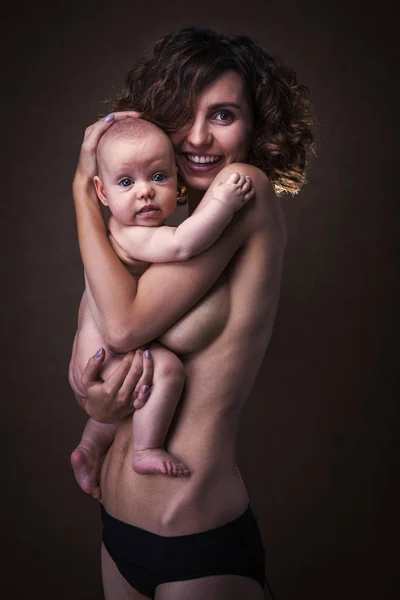 Joven madre sosteniendo un bebé en sus brazos —  Fotos de Stock