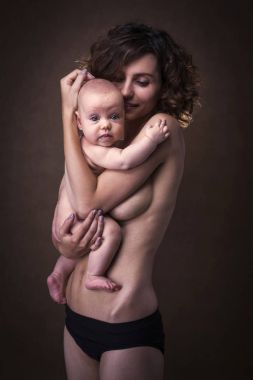 Genç anne kucağında bir bebek tutan