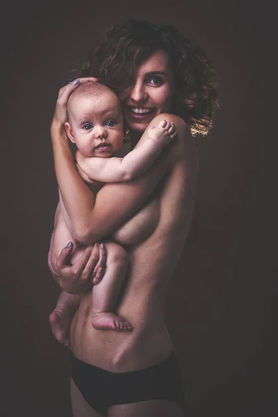 Junge Mutter hält ein Baby im Arm — Stockfoto