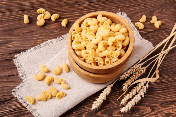 Raw elbow macaroni and rye ears in a wooden bowl — Stock Photo, Image