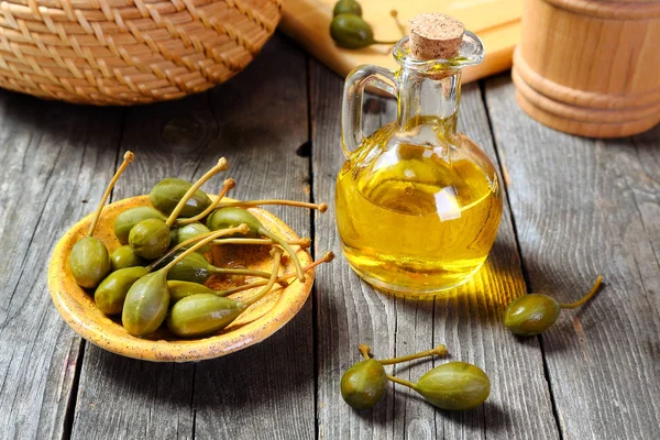 Capers in a yellow plate on a gray wooden table — Stock Photo, Image