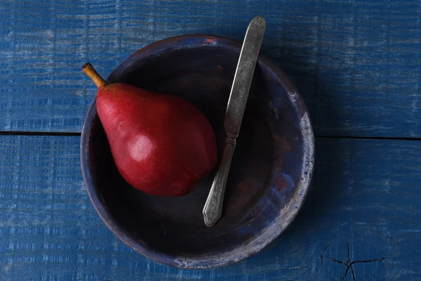 Czerwony gruszka z nożem na niebiesko — Zdjęcie stockowe