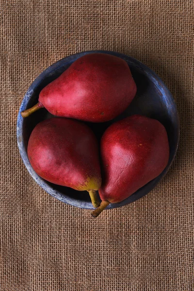 Tre pere rosse su piatto blu — Foto Stock