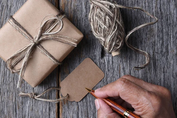 Homem escrevendo em uma etiqueta de presente de Natal em branco — Fotografia de Stock