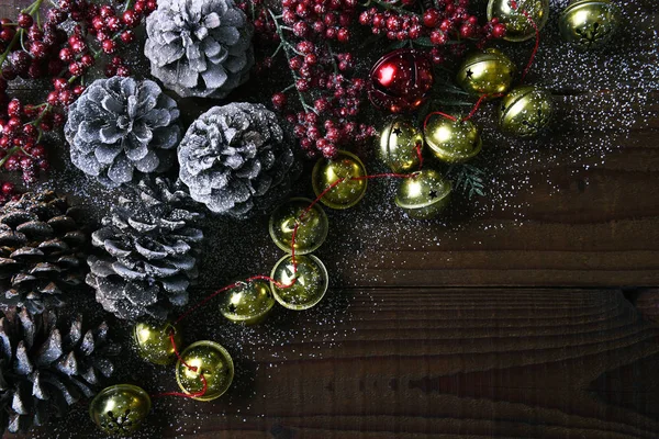 Jingle bells, pine cones and red berries on a rustic wood table — Stock Photo, Image