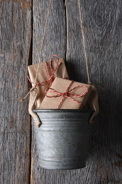 Regalos en un cubo colgado en una pared de madera rústica —  Fotos de Stock