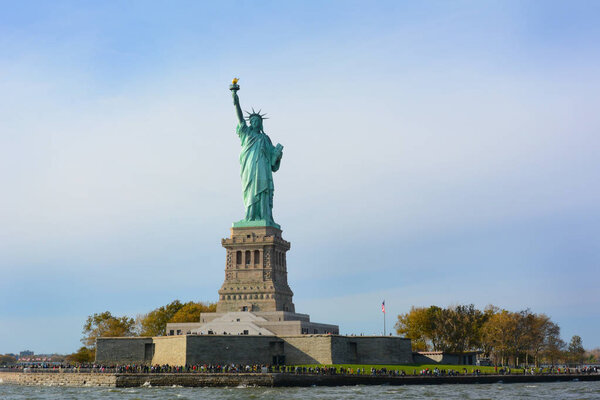 The Statue of Liberty in New York Harbor with visitors around and on the monument.