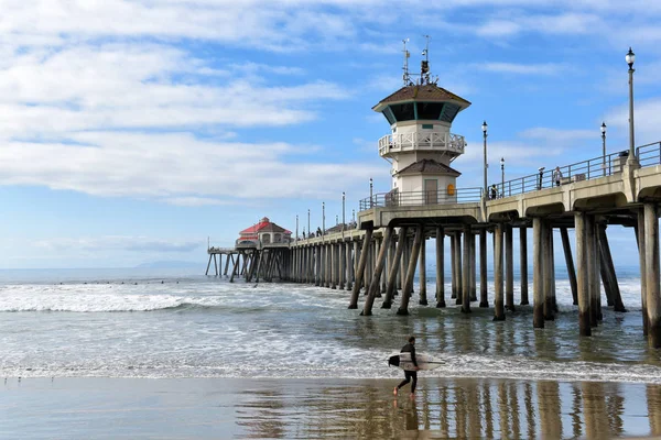 Surfer i jego deska na molo Huntington Beach. — Zdjęcie stockowe