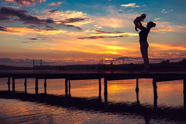 Mãe e pequeno bebê se divertindo ao pôr do sol — Fotografia de Stock