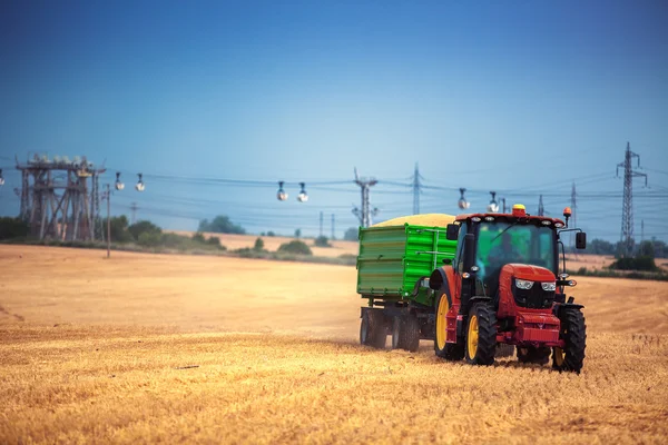 Agricultor dirigindo trator agrícola e reboque cheio de grãos — Fotografia de Stock