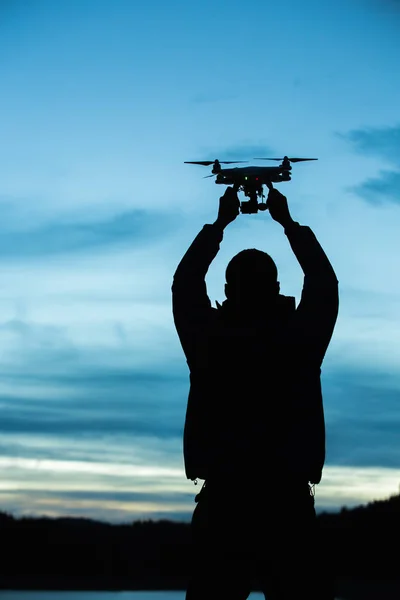 Az ember, aki a drone, a légi felvételek. sziluettjét ellen a napnyugtakor ég — Stock Fotó