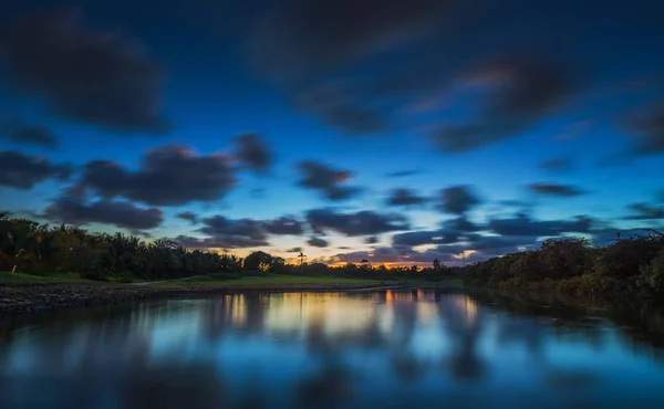 Закат над озером рядом с полем для гольфа в небольшом городке — стоковое фото
