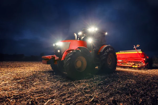 Tractor preparando tierra con cultivador de semillero por la noche — Foto de Stock