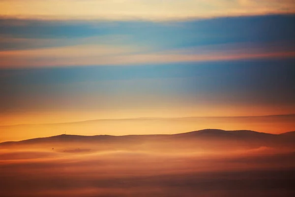 Berg laag in de ochtend zon ray en winter mist. — Stockfoto