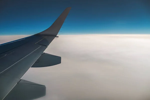 Vista das nuvens e asa do avião a partir do interior — Fotografia de Stock