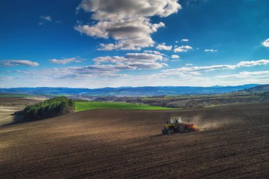 Hasat tarlasında çalışan traktörün hava görüntüsü.