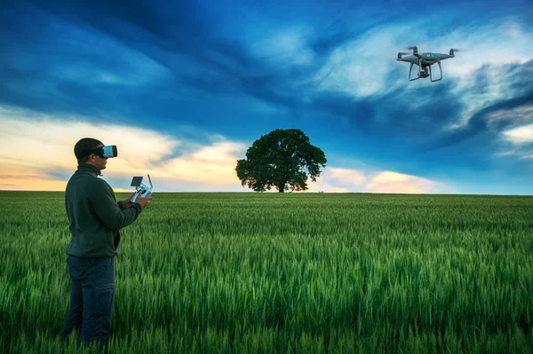 Homem com drone vestindo óculos de realidade virtual em um campo — Fotografia de Stock