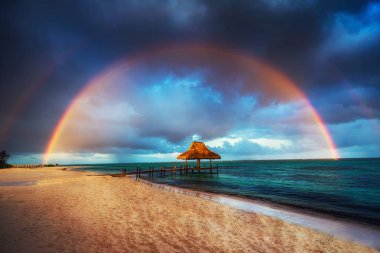 Rainbow over the Tropical beach in Punta Cana, Dominican Republi clipart