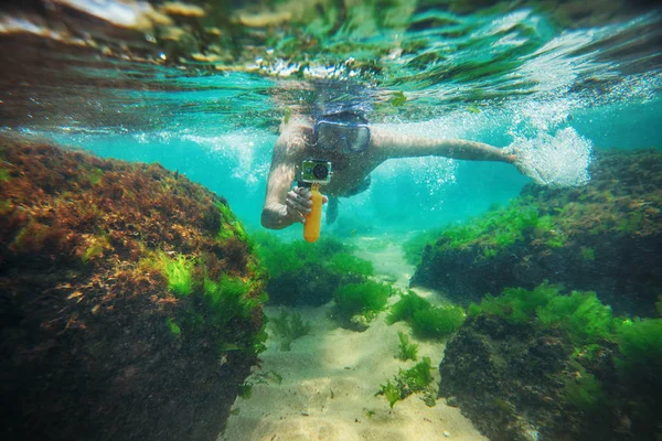 Молодой человек, плавает под водой и делает фотографии — стоковое фото