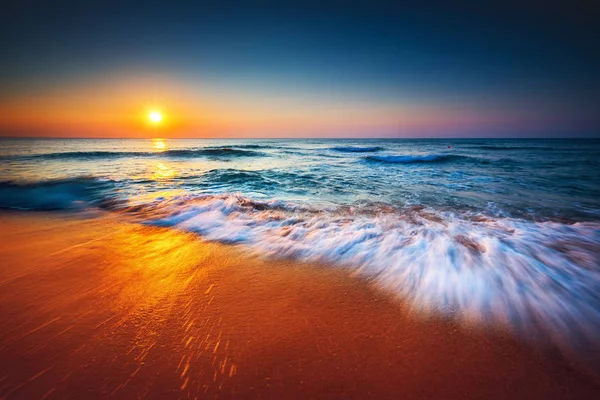 Beautiful sunrise over the sea and washing waves — Stock Photo, Image