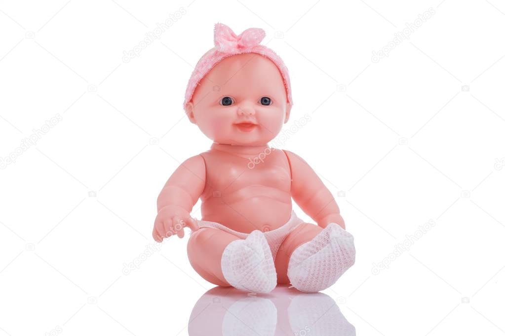 Cute little plastic baby doll with blue eyes sitting isolated