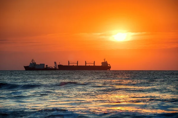 Sun setting at the sea with sailing cargo ship, sunrise view — Stock Photo, Image