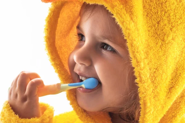 Sarı bir havlunun altında gülümseyen ve Dişlerini fırçalıyor küçük bebek — Stok fotoğraf