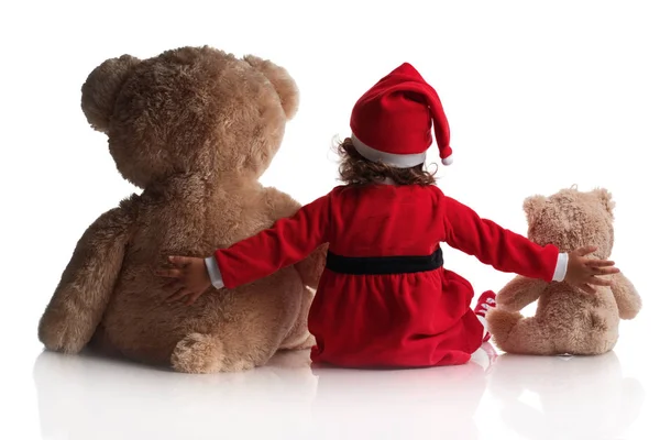 Little girl in red santa hat and teddy bear toys on white background Stock Picture