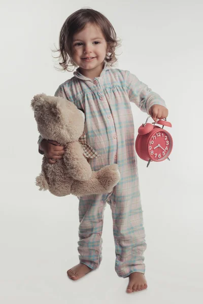 Retrato de niña con pijama con reloj despertador y peluche con pijama —  Fotos de Stock