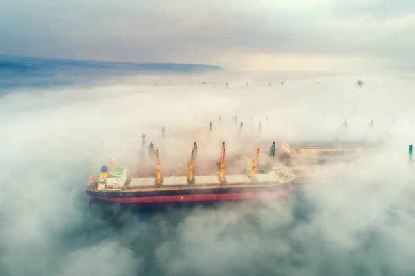 Industriekran belädt Container in einem Frachtschiff. nebliger Morgen. — Stockfoto
